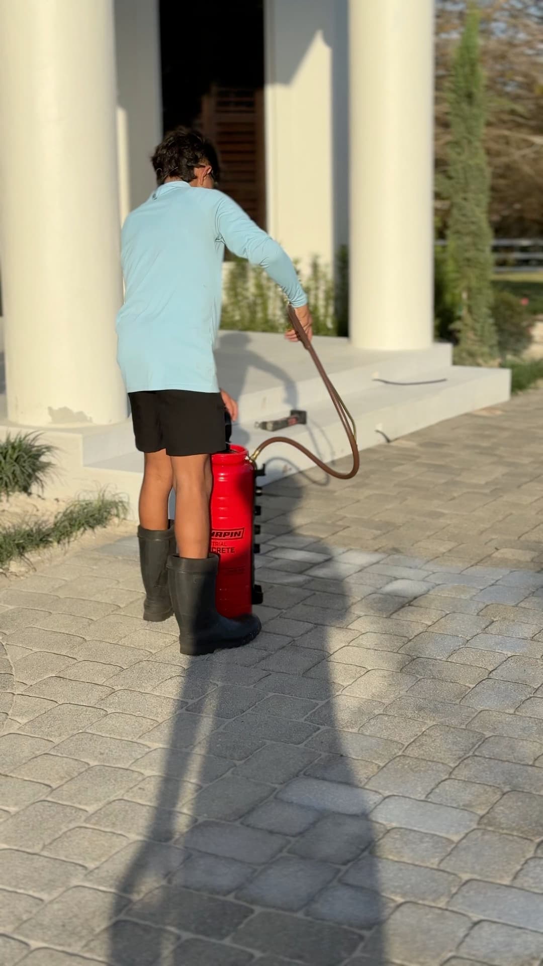 Person in blue shirt and black shorts using a fire extinguisher on a stone pathway.