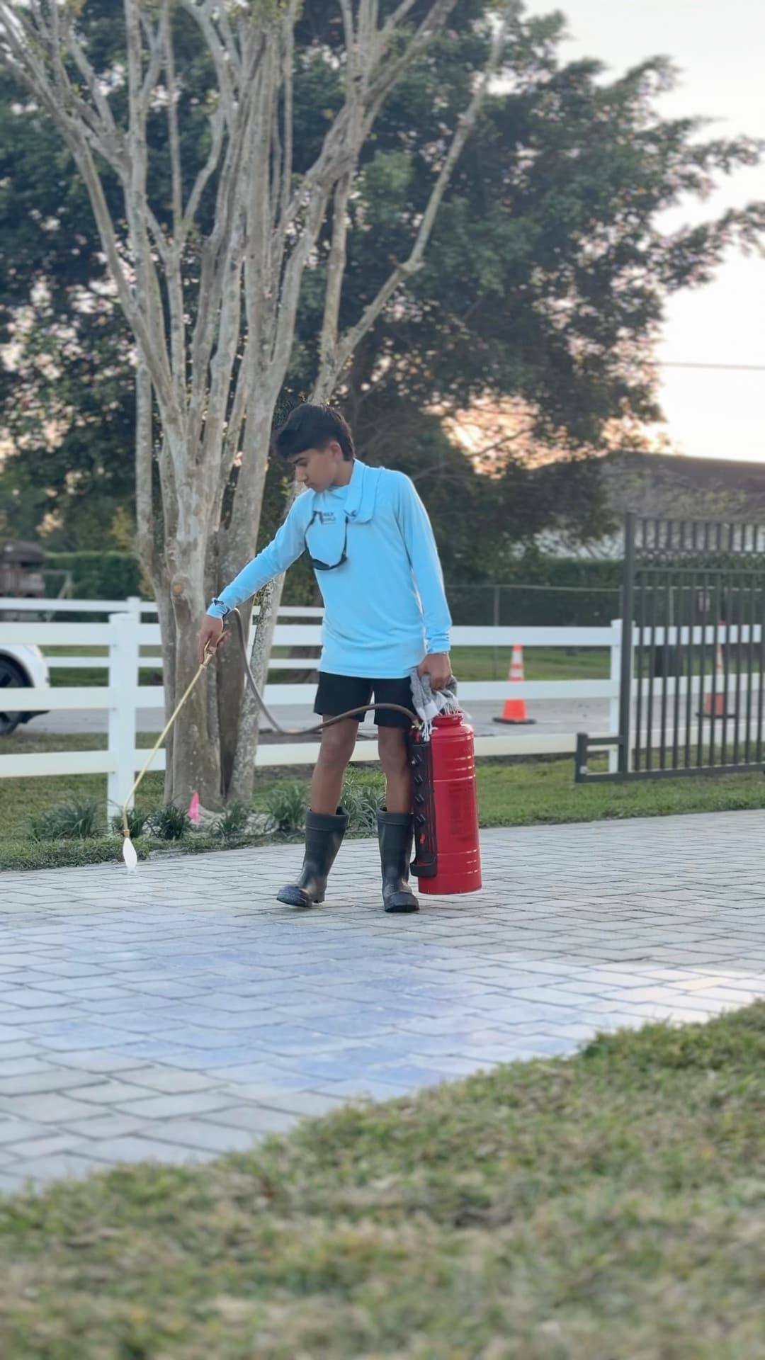 Young man in blue shirt and boots spraying a surface with a fire extinguisher nearby.