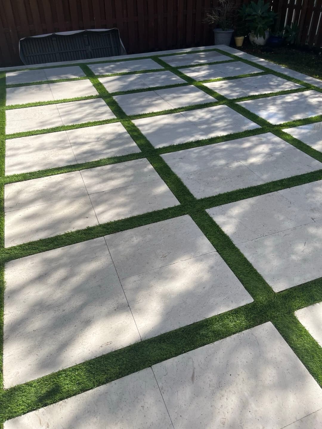 Modern patio design with stone tiles and green grass patches, creating a stylish outdoor space.