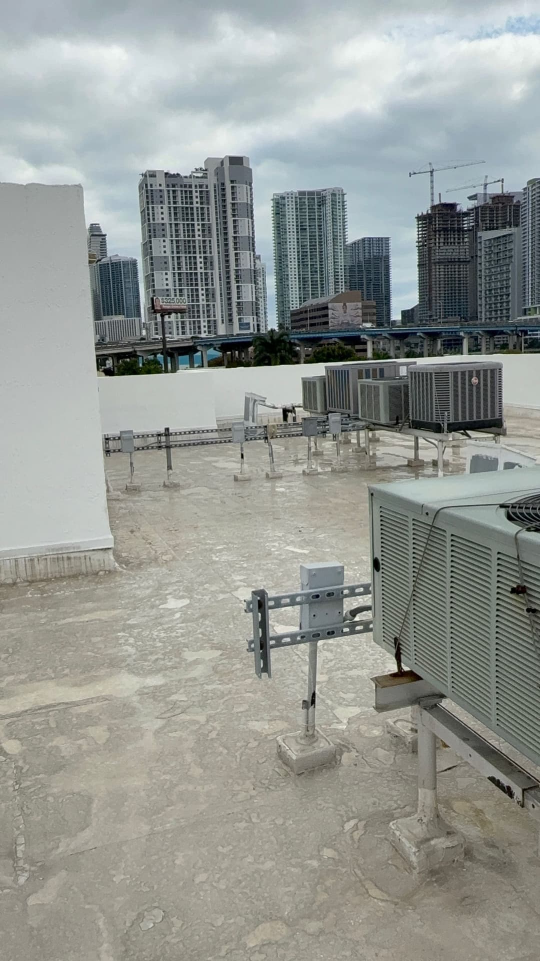 View of rooftop HVAC units on a commercial building with a city skyline in the background.